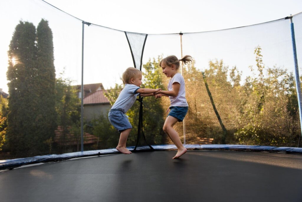 Dvě děti si hrají na trampolíně venku