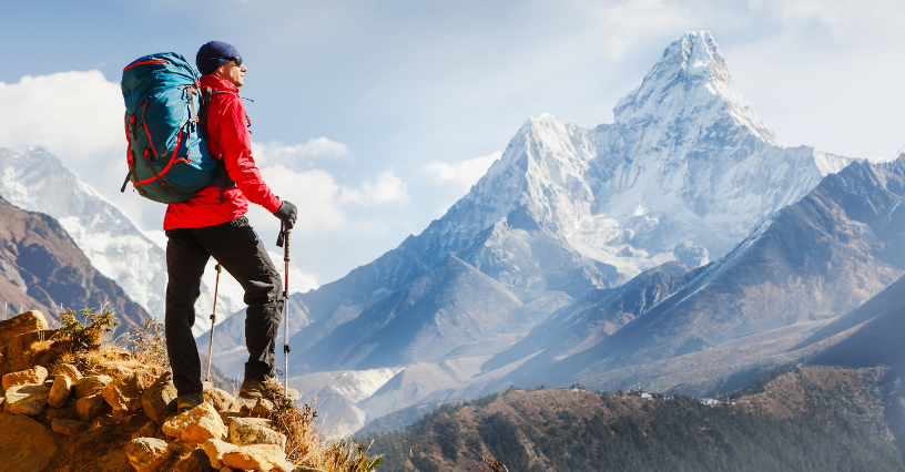 Turista na horské túře kráčí s batohem a trekovými holemi