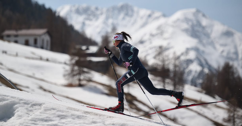 Žena na běžkách v zasněžené horské krajině