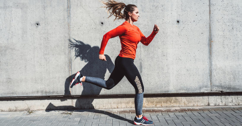 Žena běží podél betonové zdi ve sportovním oblečení