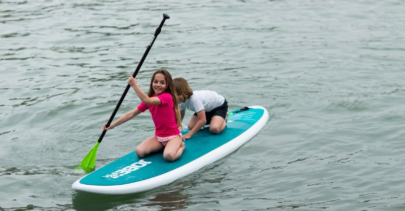 Dvě děti na paddleboardu veslují na vodě