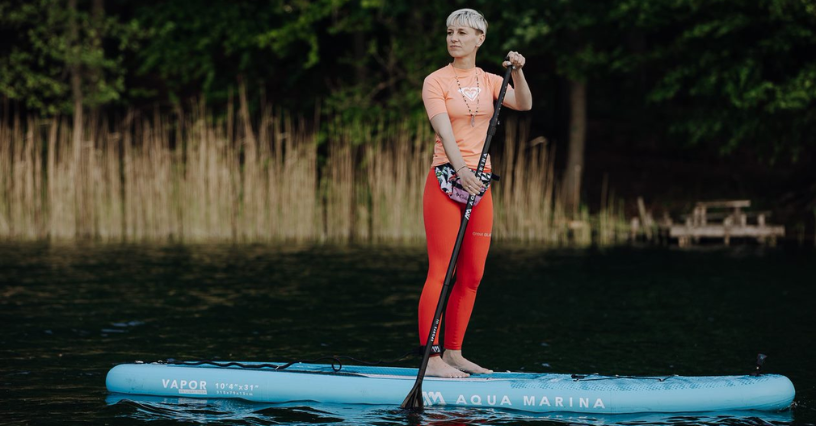 Žena pádluje na paddleboardu značky Aqua Marina na klidné vodě