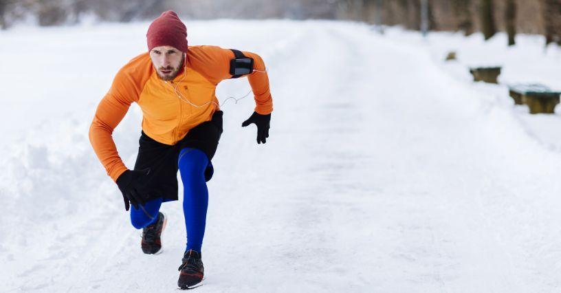 Běžec na zasněžené cestě v zimním oblečení, připraven na výkon