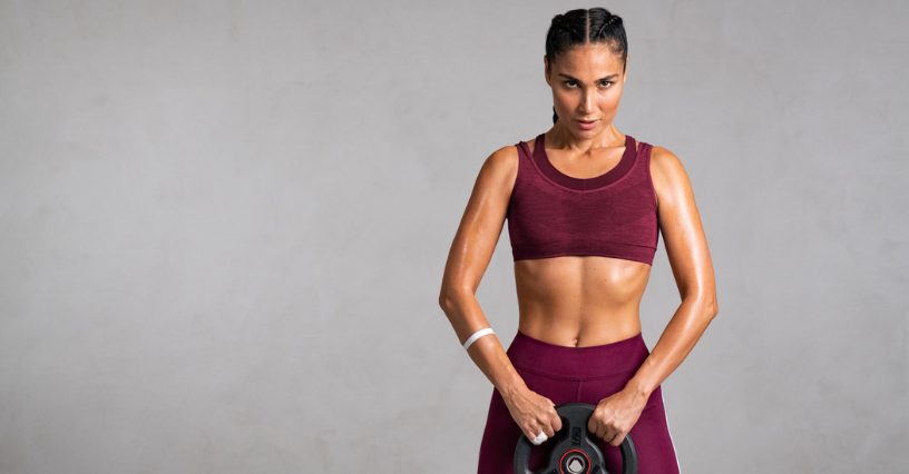 Žena drží závaží ve sportovním oblečení